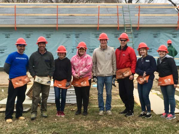 image of employee volunteers in front of a Habitat for Humanity project